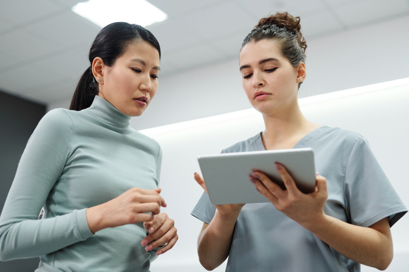 Profissional de saúde e uma mulher conversando e consultando informações em um tablet